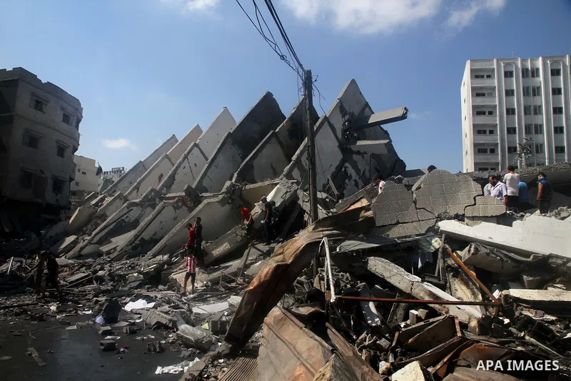 Palestinians gather around the remains of a tower building housing offices which witnesses said was destroyed by an Israeli air strike in Gaza City August 26, 2014. Israeli air strikes launched before dawn on Tuesday kil...