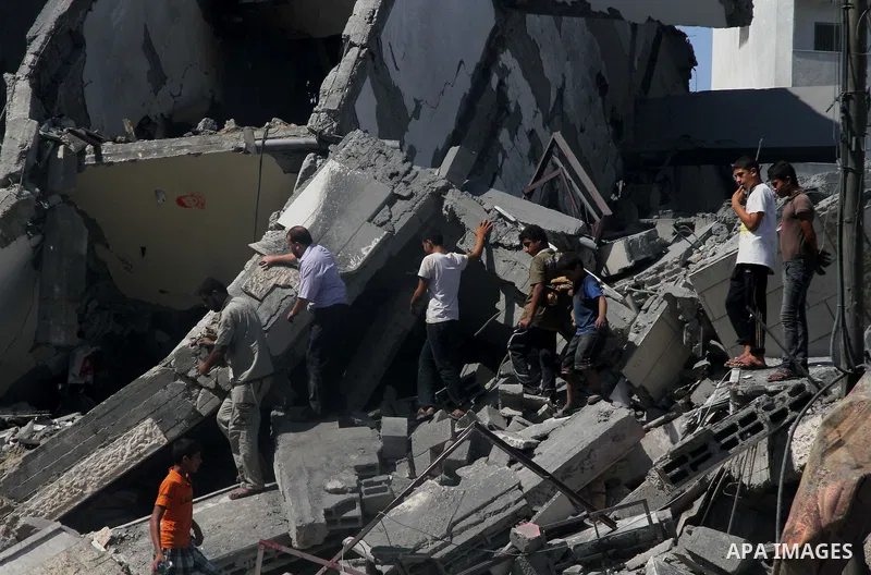 Palestinians gather around the remains of a tower building housing offices which witnesses said was destroyed by an Israeli air strike in Gaza City August 26, 2014. Israeli air strikes launched before dawn on Tuesday kil...