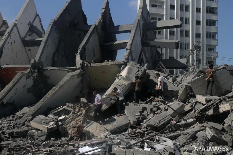 Palestinians gather around the remains of a tower building housing offices which witnesses said was destroyed by an Israeli air strike in Gaza City August 26, 2014. Israeli air strikes launched before dawn on Tuesday kil...