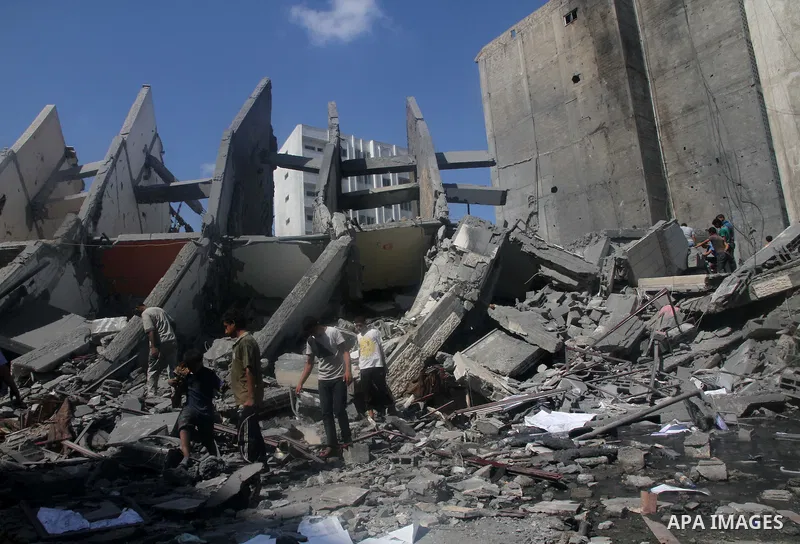 Palestinians gather around the remains of a tower building housing offices which witnesses said was destroyed by an Israeli air strike in Gaza City August 26, 2014. Israeli air strikes launched before dawn on Tuesday kil...