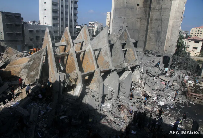 Palestinians gather around the remains of a tower building housing offices which witnesses said was destroyed by an Israeli air strike in Gaza City August 26, 2014. Israeli air strikes launched before dawn on Tuesday kil...