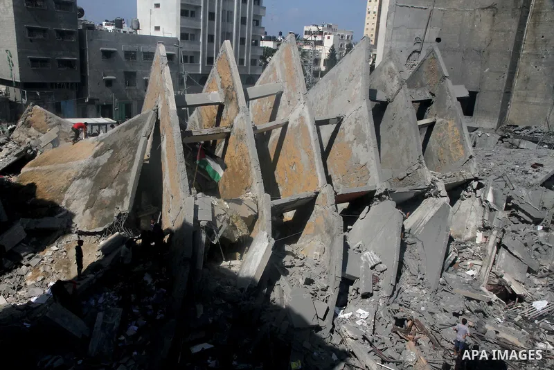 Palestinians gather around the remains of a tower building housing offices which witnesses said was destroyed by an Israeli air strike in Gaza City August 26, 2014. Israeli air strikes launched before dawn on Tuesday kil...