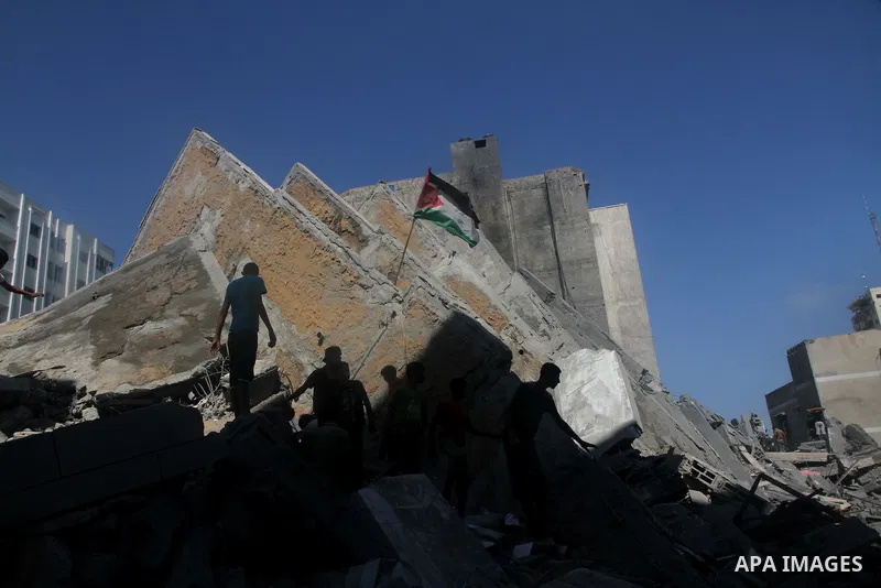 Palestinians gather around the remains of a tower building housing offices which witnesses said was destroyed by an Israeli air strike in Gaza City August 26, 2014. Israeli air strikes launched before dawn on Tuesday kil...