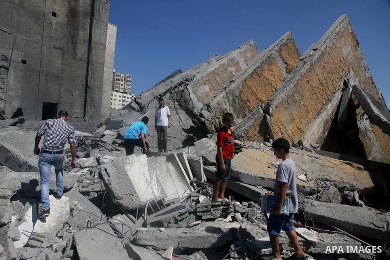 Palestinians gather around the remains of a tower building housing offices which witnesses said was destroyed by an Israeli air strike in Gaza City August 26, 2014. Israeli air strikes launched before dawn on Tuesday kil...