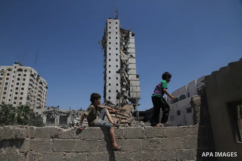 Palestinian children look at the remains of one of Gaza's tallest apartment towers, which witnesses said was hit by an Israeli air strike that destroyed much of it, in Gaza City August 26, 2014. Israeli air strikes launc...