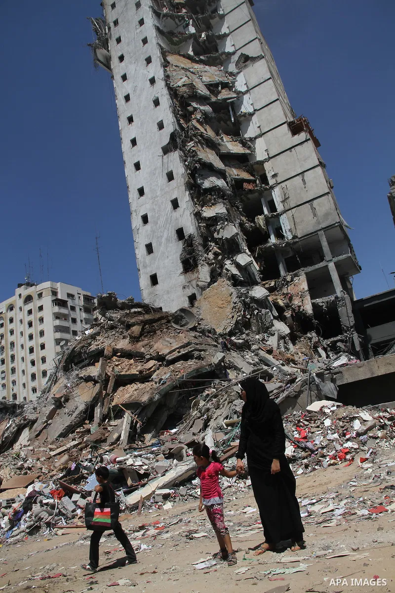 Palestinians look at the remains of one of Gaza's tallest apartment towers, which witnesses said was hit by an Israeli air strike that destroyed much of it, in Gaza City August 26, 2014. Israeli air strikes launched befo...