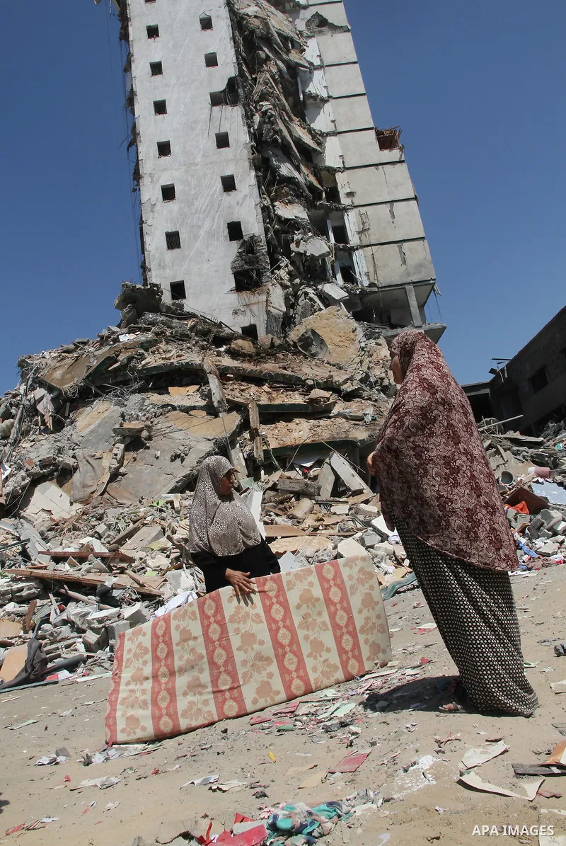 Palestinians look at the remains of one of Gaza's tallest apartment towers, which witnesses said was hit by an Israeli air strike that destroyed much of it, in Gaza City August 26, 2014. Israeli air strikes launched befo...