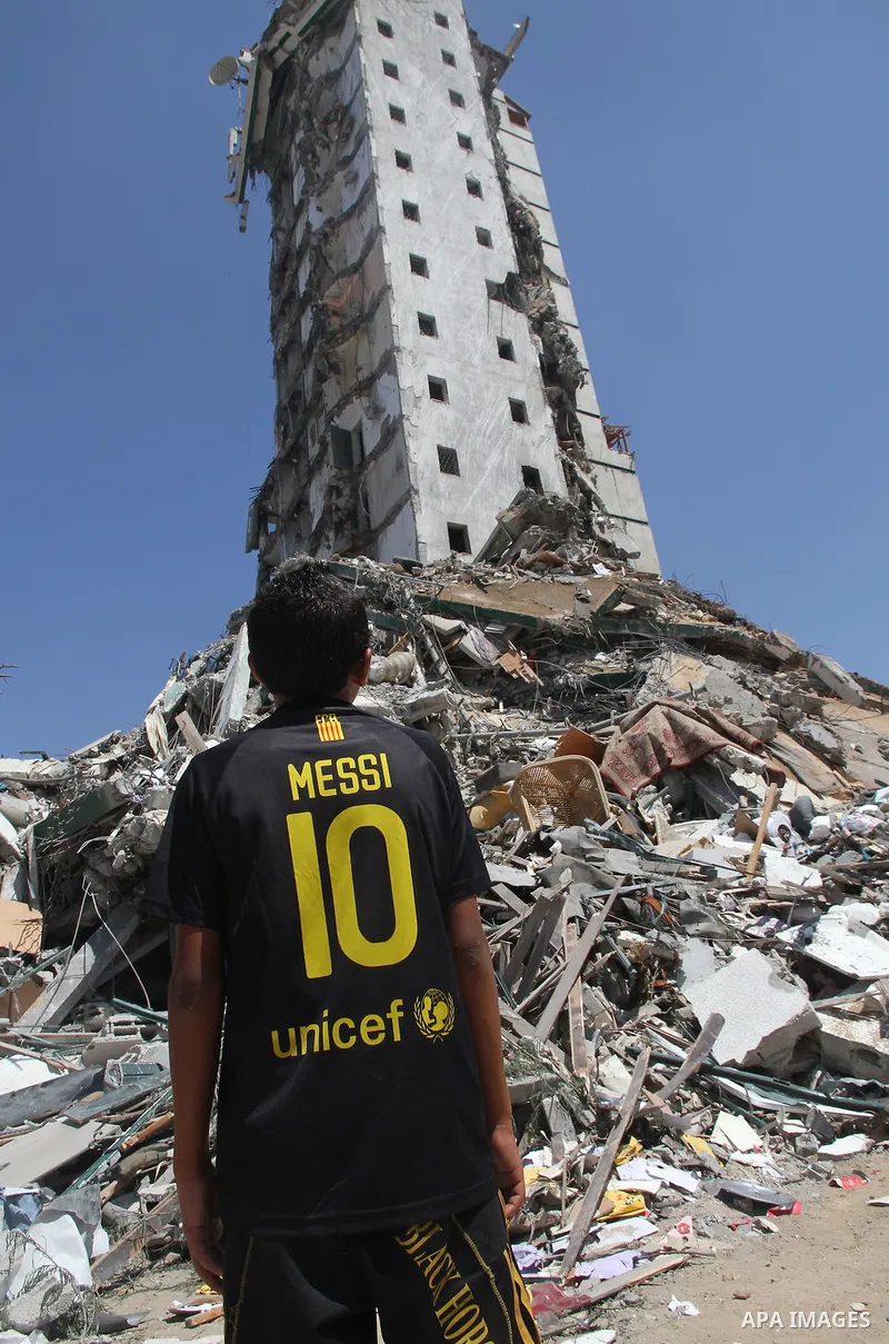 A Palestinian boy looks at the remains of one of Gaza's tallest apartment towers, which witnesses said was hit by an Israeli air strike that destroyed much of it, in Gaza City August 26, 2014. Israeli air strikes launche...