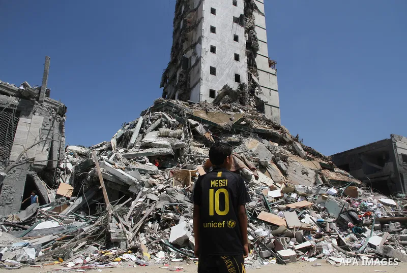 A Palestinian boy looks at the remains of one of Gaza's tallest apartment towers, which witnesses said was hit by an Israeli air strike that destroyed much of it, in Gaza City August 26, 2014. Israeli air strikes launche...
