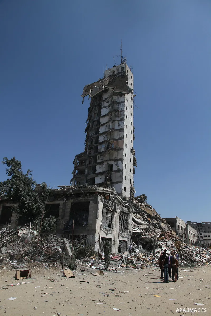 Palestinians look at the remains of one of Gaza's tallest apartment towers, which witnesses said was hit by an Israeli air strike that destroyed much of it, in Gaza City August 26, 2014. Israeli air strikes launched befo...