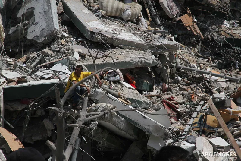 A Palestinian man sits on the remains of one of Gaza's tallest apartment towers, which witnesses said was hit by an Israeli air strike that destroyed much of it, in Gaza City August 26, 2014. Israeli air strikes launched...