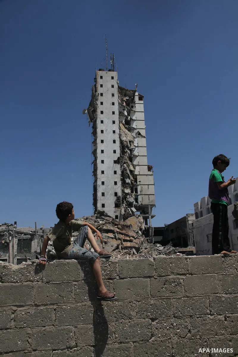 Palestinian children look at the remains of one of Gaza's tallest apartment towers, which witnesses said was hit by an Israeli air strike that destroyed much of it, in Gaza City August 26, 2014. Israeli air strikes launc...