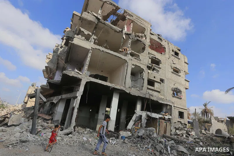 Palestinian boys walk past destroyed homes in their neighborhood as they head home in Shejaiya on August 27, 2014. The open-ended ceasefire in the Gaza war between Israel and the Palestinians held on Wednesday as Prime M...