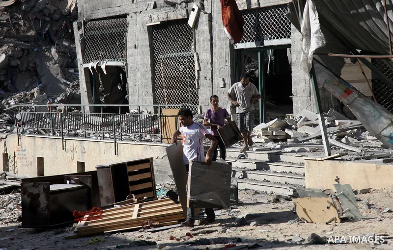 Palestinians collect their belongings from under the rubble of one of Gaza's tallest apartment towers, which witnesses said was hit by an Israeli air strike that destroyed much of it, in Gaza City August 27, 2014. The op...