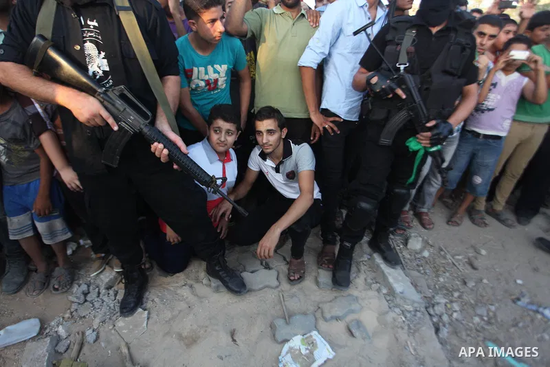Palestinian militants of Izzedine al-Qassam Brigades, military wing of Hamas, and their supporters celebrate a victory rally at the debris of destroyed houses in Shijaiyah, neighborhood of Gaza City, in the northern Gaza...