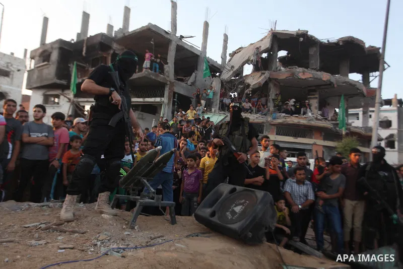 Palestinian militants of Izzedine al-Qassam Brigades, military wing of Hamas, and their supporters celebrate a victory rally at the debris of destroyed houses in Shijaiyah, neighborhood of Gaza City, in the northern Gaza...