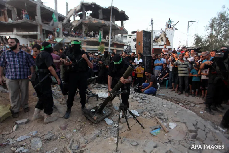 Palestinian militants of Izzedine al-Qassam Brigades, military wing of Hamas, and their supporters celebrate a victory rally at the debris of destroyed houses in Shijaiyah, neighborhood of Gaza City, in the northern Gaza...