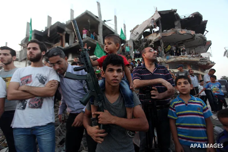 Palestinian militants of Izzedine al-Qassam Brigades, military wing of Hamas, and their supporters celebrate a victory rally at the debris of destroyed houses in Shijaiyah, neighborhood of Gaza City, in the northern Gaza...