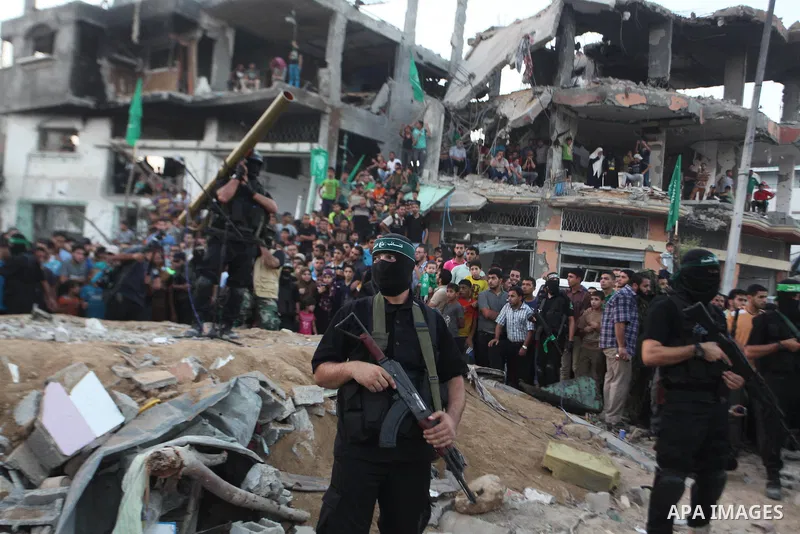Palestinian militants of Izzedine al-Qassam Brigades, military wing of Hamas, and their supporters celebrate a victory rally at the debris of destroyed houses in Shijaiyah, neighborhood of Gaza City, in the northern Gaza...