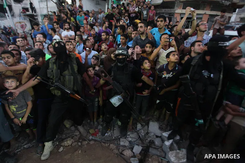Palestinian militants of Izzedine al-Qassam Brigades, military wing of Hamas, and their supporters celebrate a victory rally at the debris of destroyed houses in Shijaiyah, neighborhood of Gaza City, in the northern Gaza...