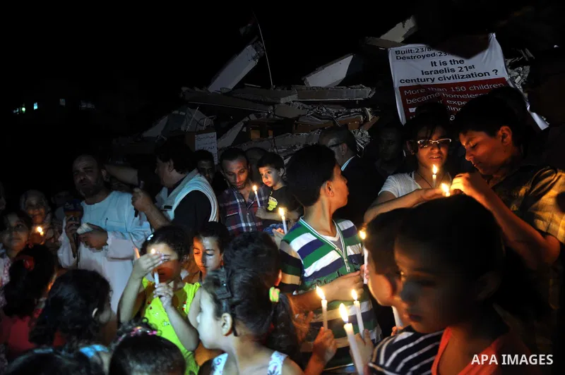 Palestinian Families hold candles during a protest in front of the remains El Zafer Tower destroyed in an israeli airstrike, in Gaza city, on Aug. 27, 2014. The open-ended ceasefire in the Gaza war between Israel and the...