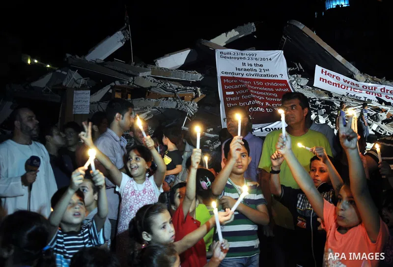 Palestinian Families hold candles during a protest in front of the remains El Zafer Tower destroyed in an israeli airstrike, in Gaza city, on Aug. 27, 2014. The open-ended ceasefire in the Gaza war between Israel and the...