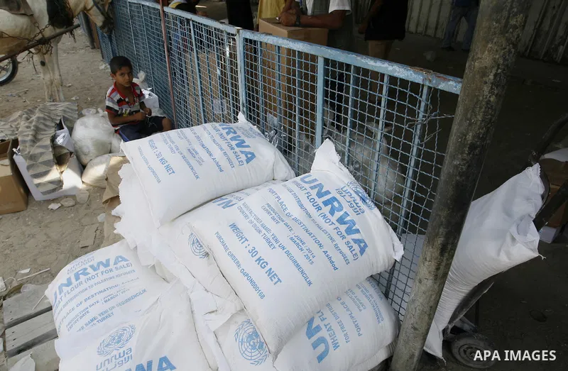 A Palestinian boy sits near bags of flour in centre of the United Nations Relief and Works Agency (UNRWA) in Rafah in southern Gaza strip on August 28, 2014. The aid was sent to the U.N. office to be distributed in the G...