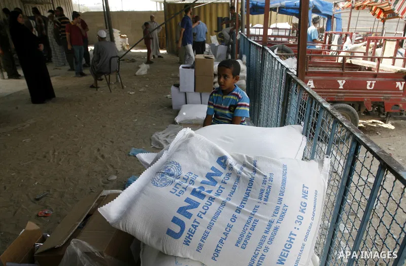A Palestinian boy sits near bags of flour in centre of the United Nations Relief and Works Agency (UNRWA) in Rafah in southern Gaza strip on August 28, 2014. The aid was sent to the U.N. office to be distributed in the G...