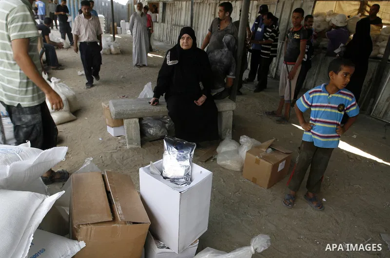 Palestinians wait to receive food supplies from a distribution centre of the United Nations Relief and Works Agency (UNRWA) in Rafah in southern Gaza strip on August 28, 2014. The aid was sent to the U.N. office to be di...