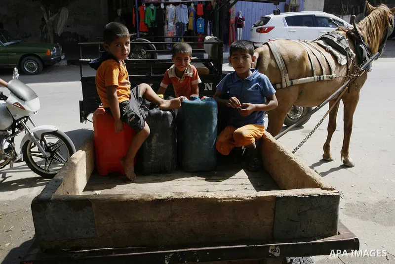 Palestinians children fill plastic bottles and water containers with drinking water from a public tap in Rafah in the southern Gaza Strip on August 28, 2014. Israel and Palestinians both boasted of victory in the Gaza wa...