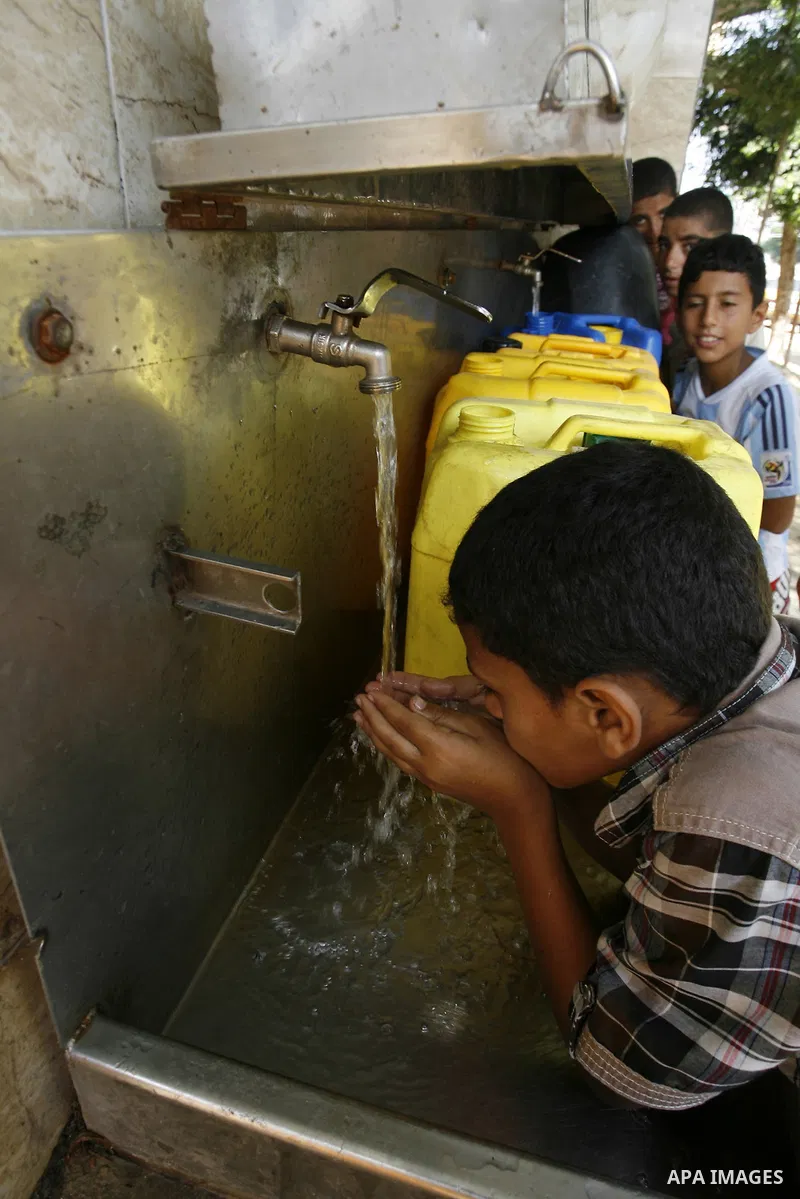 Palestinians children fill plastic bottles and water containers with drinking water from a public tap in Rafah in the southern Gaza Strip on August 28, 2014. Israel and Palestinians both boasted of victory in the Gaza wa...