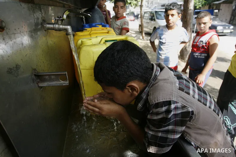 Palestinians children fill plastic bottles and water containers with drinking water from a public tap in Rafah in the southern Gaza Strip on August 28, 2014. Israel and Palestinians both boasted of victory in the Gaza wa...