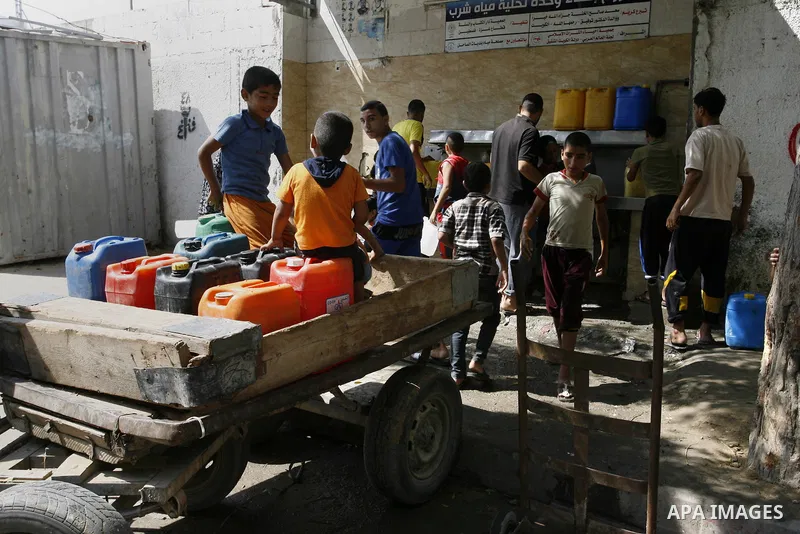 Palestinians children fill plastic bottles and water containers with drinking water from a public tap in Rafah in the southern Gaza Strip on August 28, 2014. Israel and Palestinians both boasted of victory in the Gaza wa...