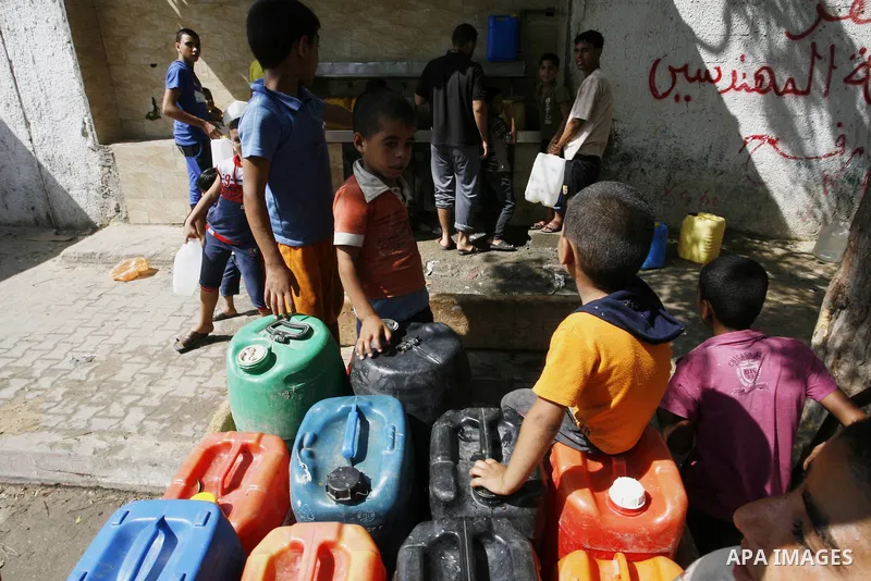 Palestinians children fill plastic bottles and water containers with drinking water from a public tap in Rafah in the southern Gaza Strip on August 28, 2014. Israel and Palestinians both boasted of victory in the Gaza wa...
