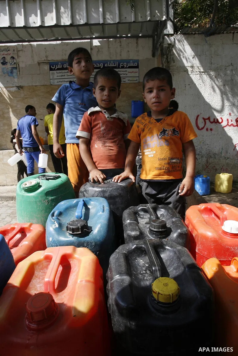 Palestinians children fill plastic bottles and water containers with drinking water from a public tap in Rafah in the southern Gaza Strip on August 28, 2014. Israel and Palestinians both boasted of victory in the Gaza wa...