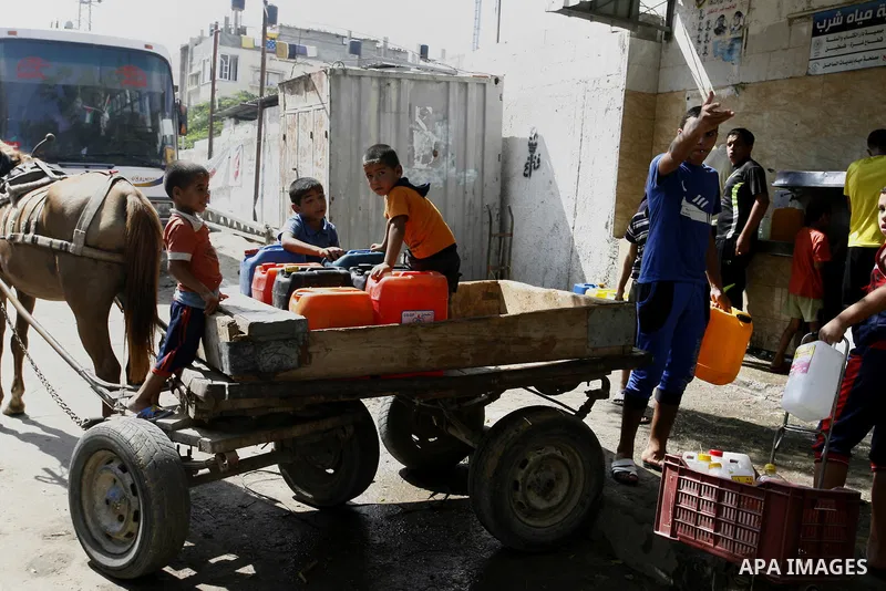 Palestinians children fill plastic bottles and water containers with drinking water from a public tap in Rafah in the southern Gaza Strip on August 28, 2014. Israel and Palestinians both boasted of victory in the Gaza wa...