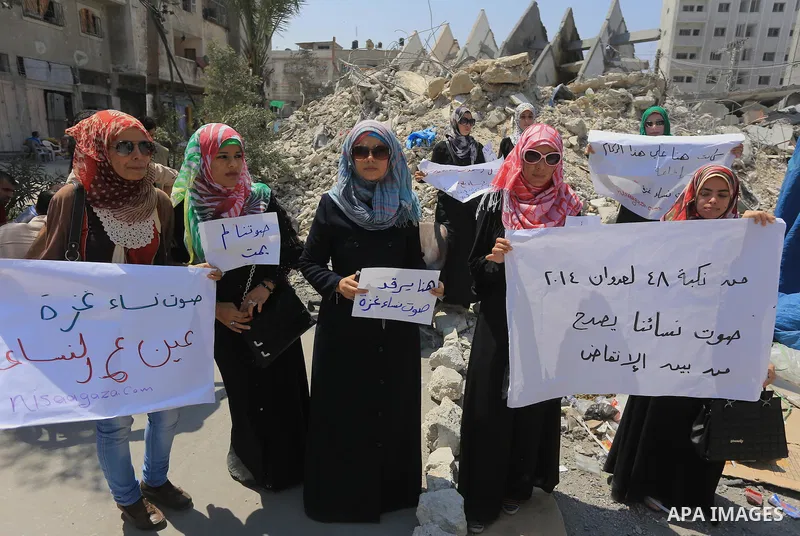Palestinian women hold banners as they take part a protest in front of the El-Basha Tower destroyed by Israeli airstrike in Gaza city on August 28, 2014. Israel and Palestinians both boasted of victory in the Gaza war bu...