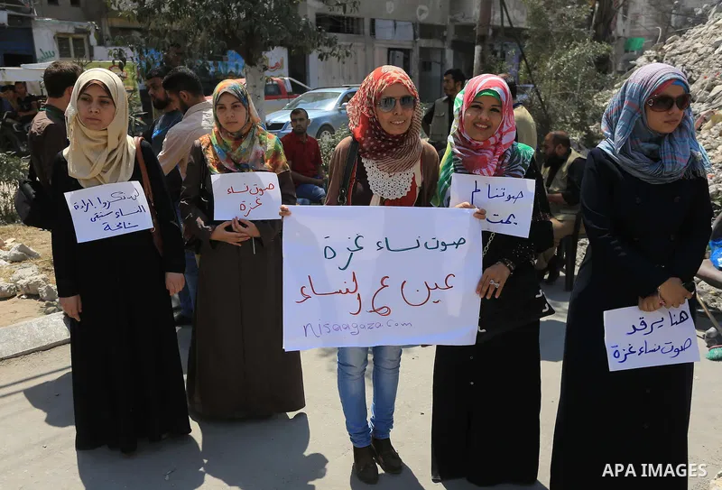 Palestinian women hold banners as they take part a protest in front of the El-Basha Tower destroyed by Israeli airstrike in Gaza city on August 28, 2014. Israel and Palestinians both boasted of victory in the Gaza war bu...