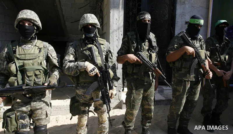 Members of the Ezzedine al-Qassam Brigades, the Islamist movement's armed wing, stand guard in front of a portrait of killed senior Hamas commander Mohammed Abu Shamala on August 28, 2014 during a visit of the latter's f...