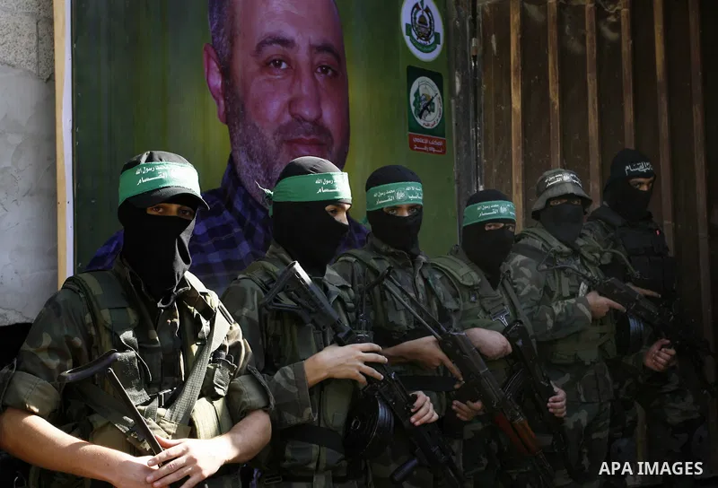 Members of the Ezzedine al-Qassam Brigades, the Islamist movement's armed wing, stand guard in front of a portrait of killed senior Hamas commander Mohammed Abu Shamala on August 28, 2014 during a visit of the latter's f...