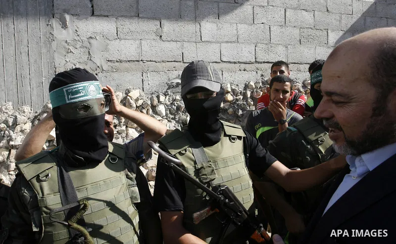 Hamas political leader Moussa Abu Marzouk shakes hands with a Hamas militant as he visits the mourning tent of senior Hamas commander Mohammed Abu Shammala (seen in posters), who was killed by an Israeli air strike durin...