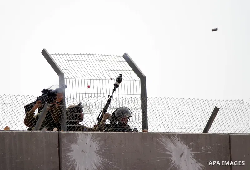 Members of the Israeli security forces fire a tear gas canister from the top of Isreal's controversial separation barrier during clashes with Palestinians demonstrators in the village of Bilin, near the West Bank city of...