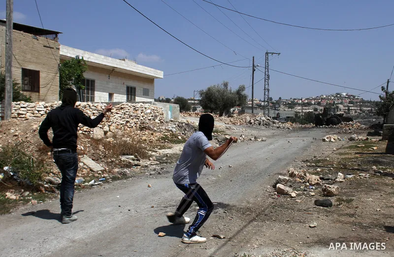 Palestinian protester hurls stones at Israeli soldiers during weekly clashes over the Jewish settlement of Qadomem at Kofr Qadom village, near West Bank city of Nablus, 29 August 2014. Photo by Nedal Eshtayah