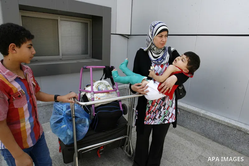 A Palestinian mother carries his wounded son as they wait to be given the permission to cross into Egypt at the Rafah border crossing in the southern Gaza Strip, on August 28, 2014. The Rafah crossing with Egypt is Gaza'...
