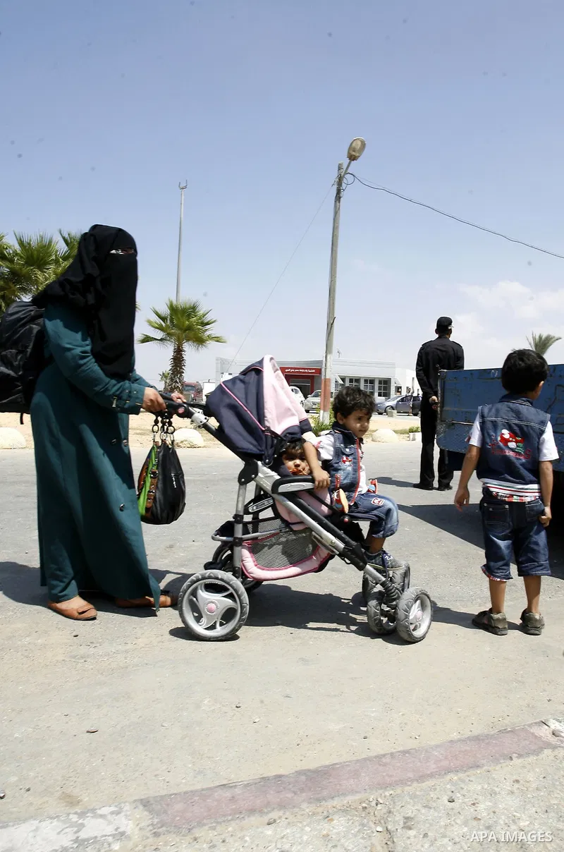 A Palestinian mother wheels his son as they wait to be given the permission to cross into Egypt at the Rafah border crossing in the southern Gaza Strip, on August 28, 2014. The Rafah crossing with Egypt is Gaza's only ga...