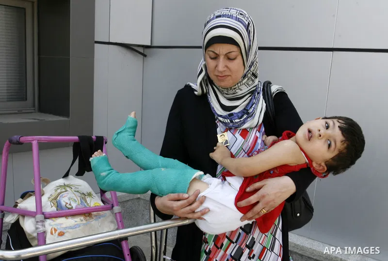 A Palestinian mother carries his wounded son as they wait to be given the permission to cross into Egypt at the Rafah border crossing in the southern Gaza Strip, on August 28, 2014. The Rafah crossing with Egypt is Gaza'...