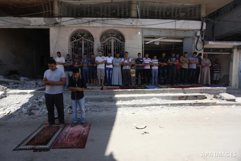 A collapsed minaret is seen as Palestinians perform Friday prayers outside the remains of a mosque, which witnesses said was hit by an Israeli air strike during a seven-week Israeli offensive in Gaza City August 29, 2014...