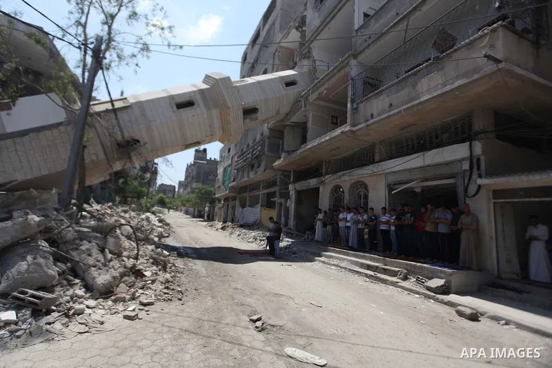A collapsed minaret is seen as Palestinians perform Friday prayers outside the remains of a mosque, which witnesses said was hit by an Israeli air strike during a seven-week Israeli offensive in Gaza City August 29, 2014...