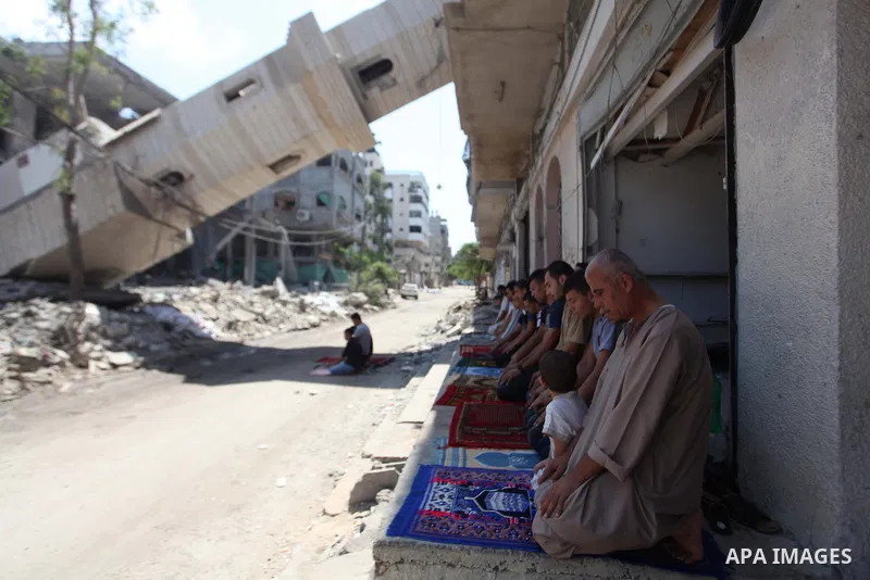 A collapsed minaret is seen as Palestinians perform Friday prayers outside the remains of a mosque, which witnesses said was hit by an Israeli air strike during a seven-week Israeli offensive in Gaza City August 29, 2014...