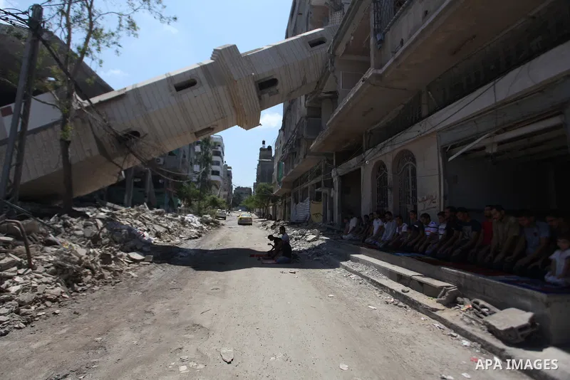A collapsed minaret is seen as Palestinians perform Friday prayers outside the remains of a mosque, which witnesses said was hit by an Israeli air strike during a seven-week Israeli offensive in Gaza City August 29, 2014...